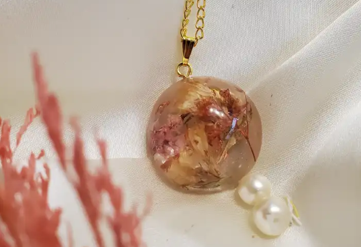 Gullrung round resin pendant with real pink and cream dried flowers on a gold chain